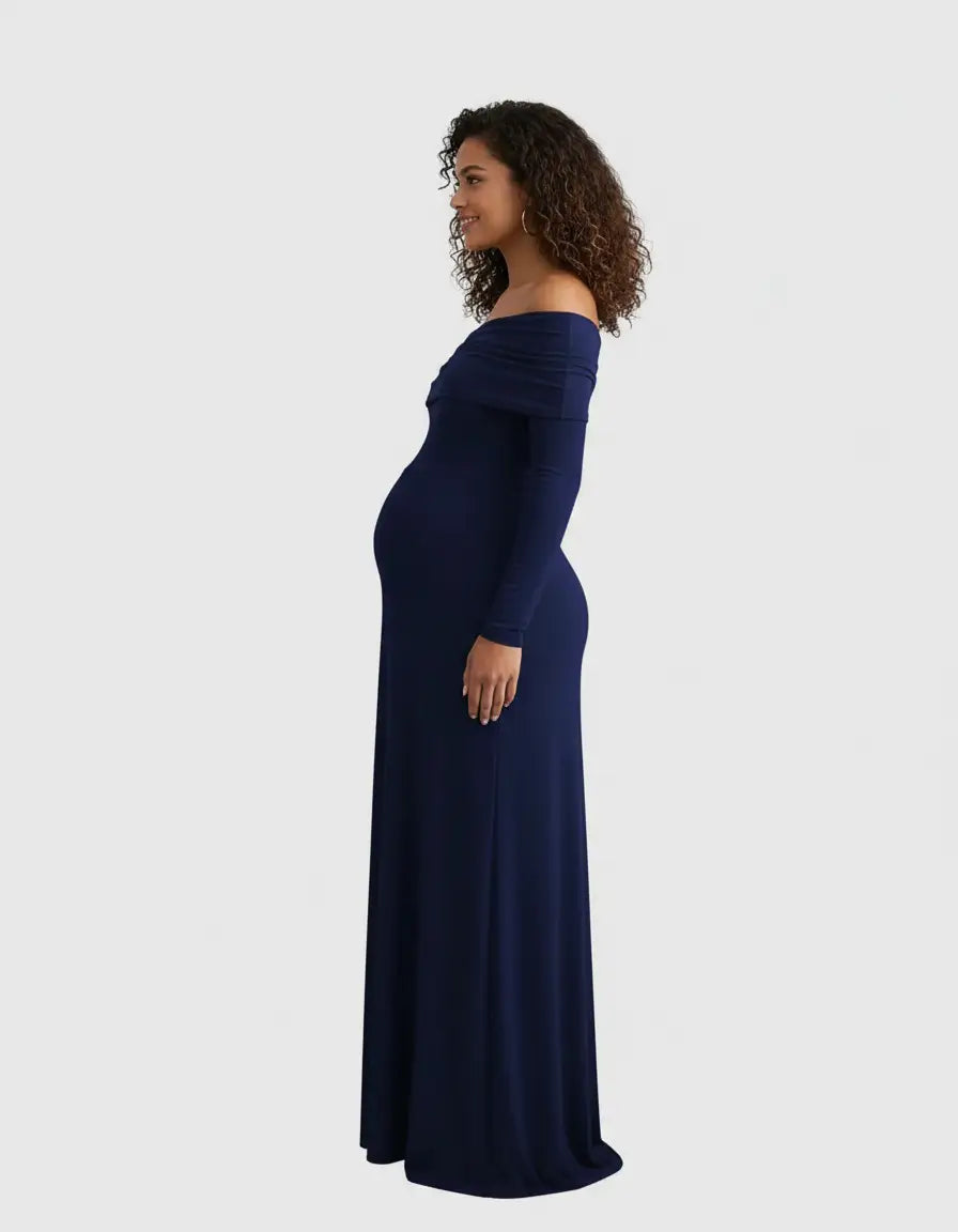 Pregnant woman in a navy off-shoulder cross-back maternity gown, side view.