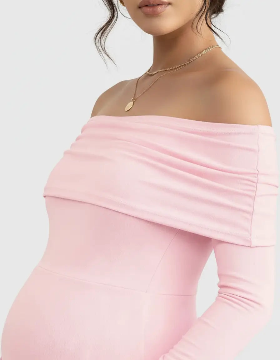 Pink off-shoulder cross-back maternity gown with long sleeves, ruched neckline, and gold necklace.
