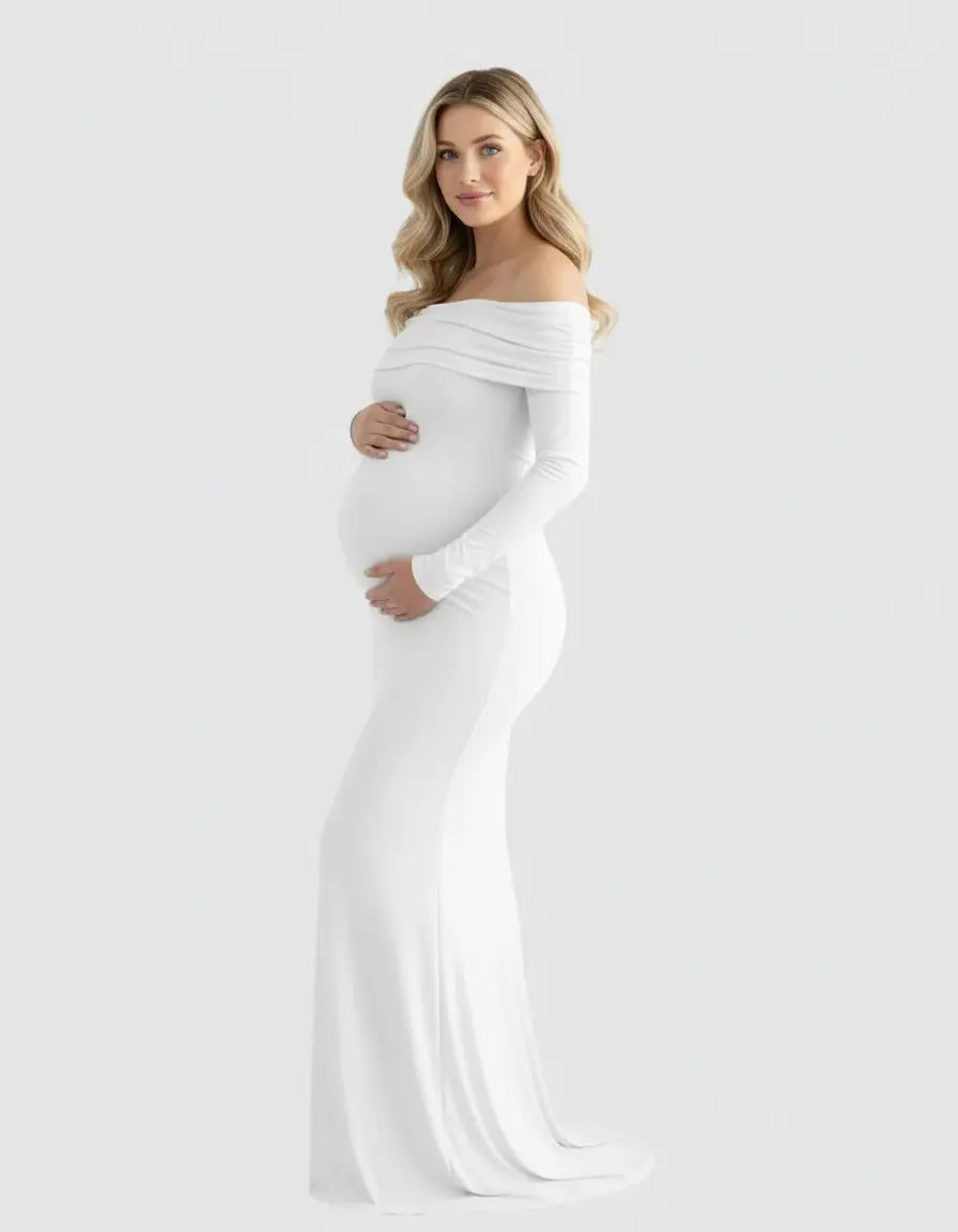 Blonde pregnant woman in a white off-shoulder, long-sleeve, cross-back maternity gown.