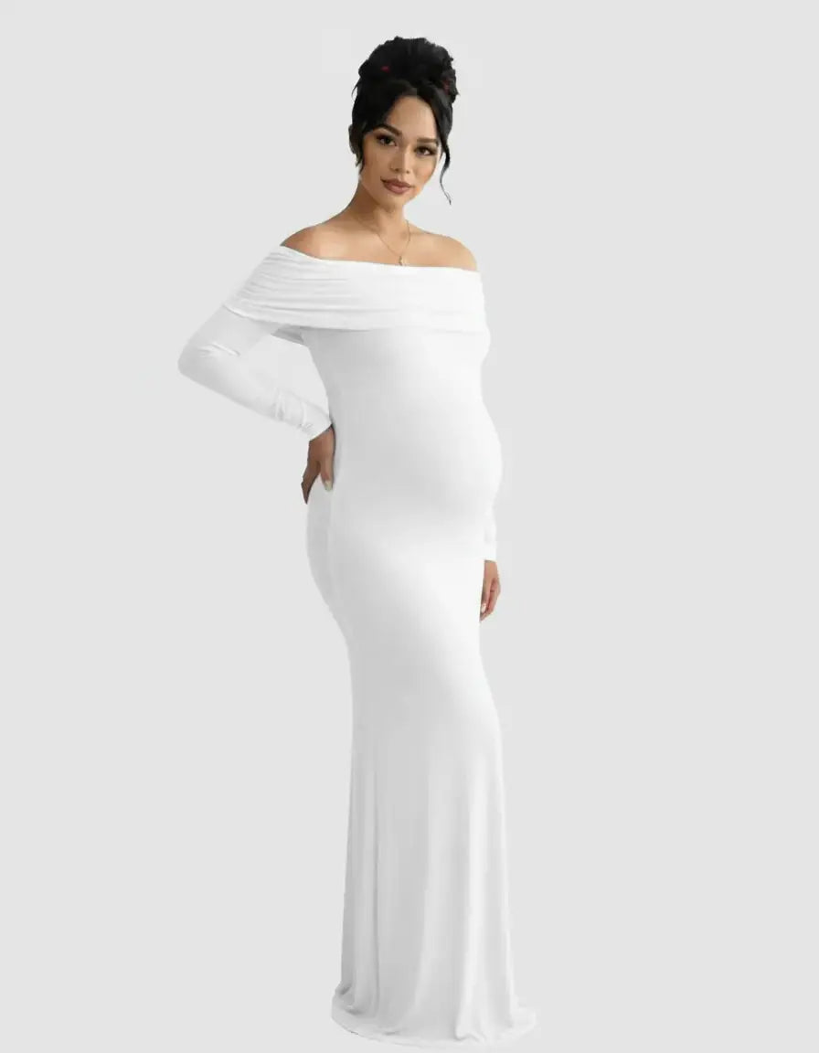 Pregnant woman in a white off-shoulder, long-sleeve, cross-back maternity gown.
