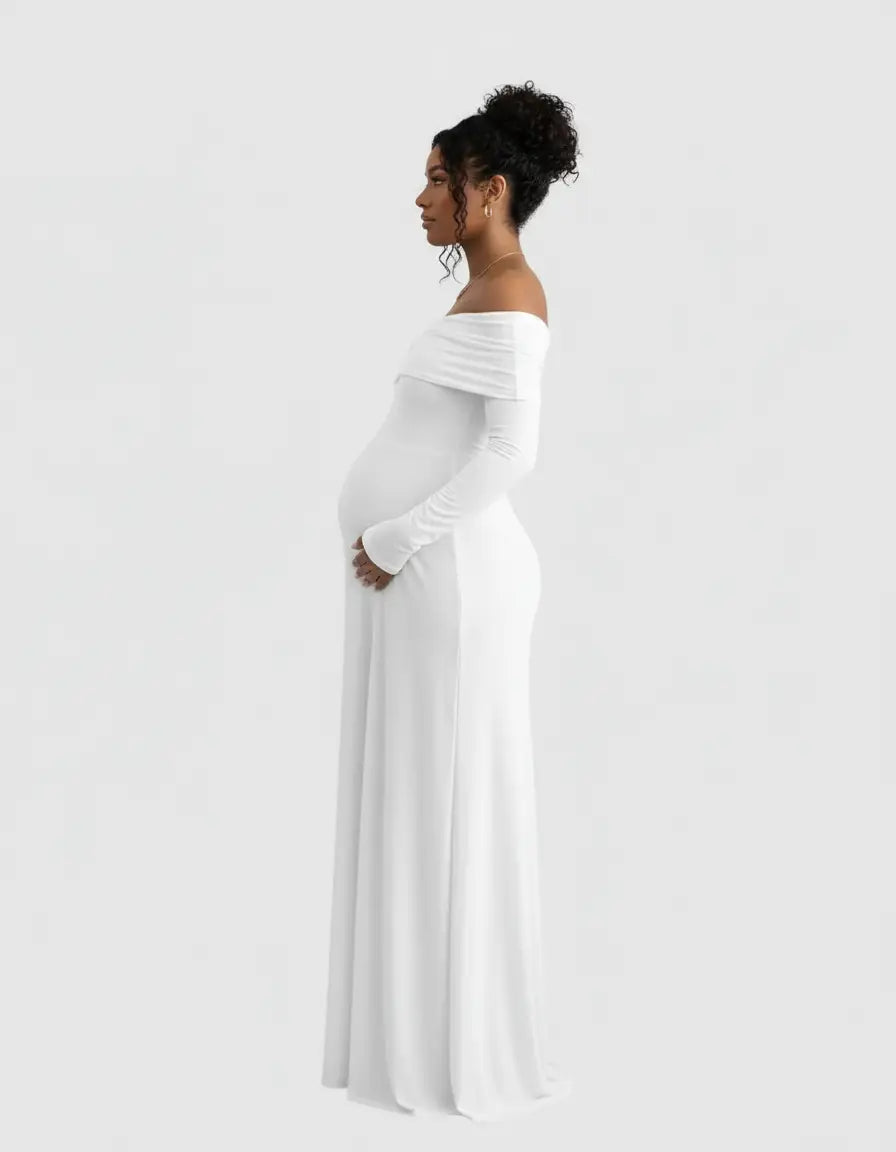 Pregnant woman in a white off-shoulder, long-sleeve, cross-back maternity gown.