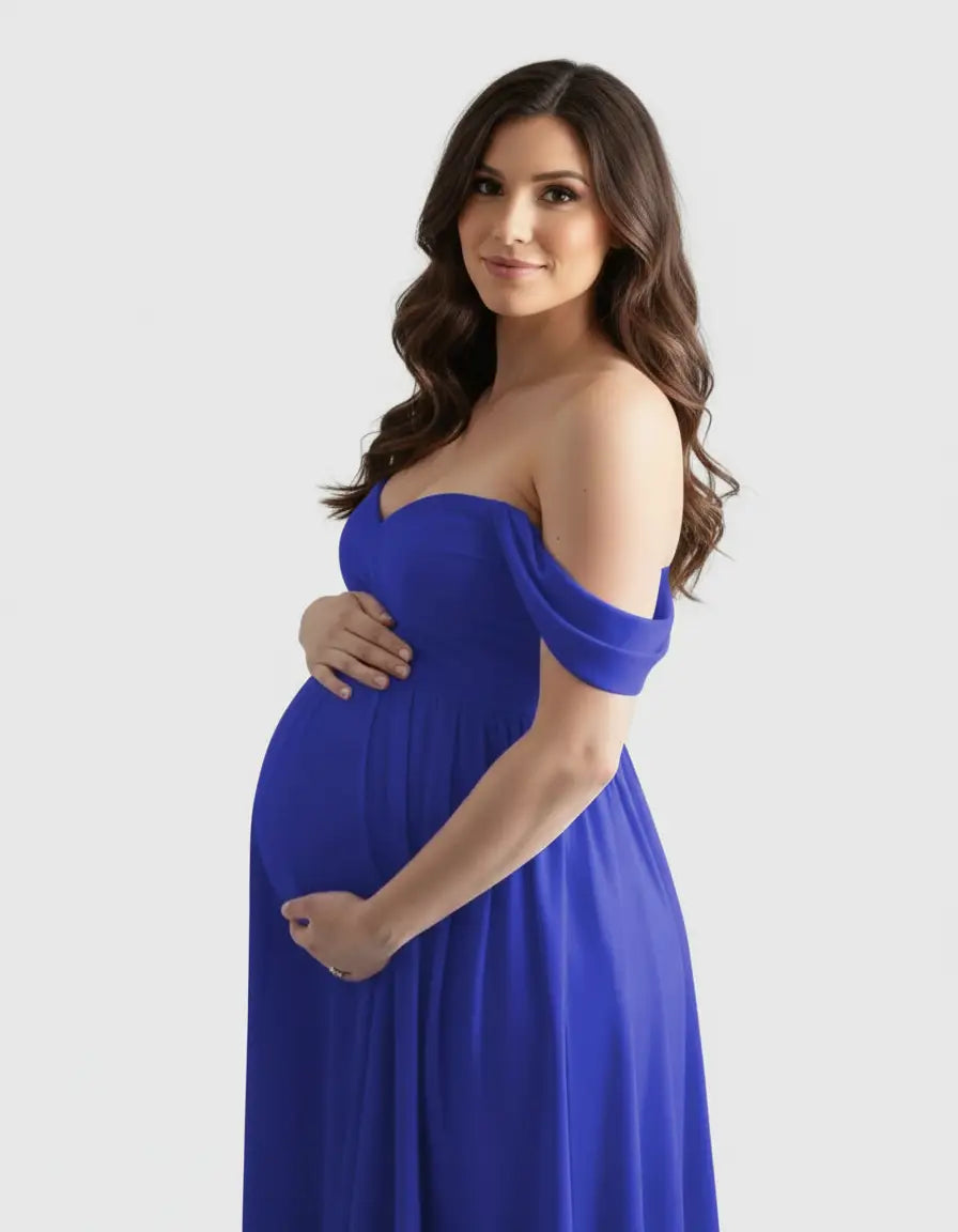 Pregnant woman in a flowing royal blue off-shoulder maternity photoshoot gown, cradling her bump.