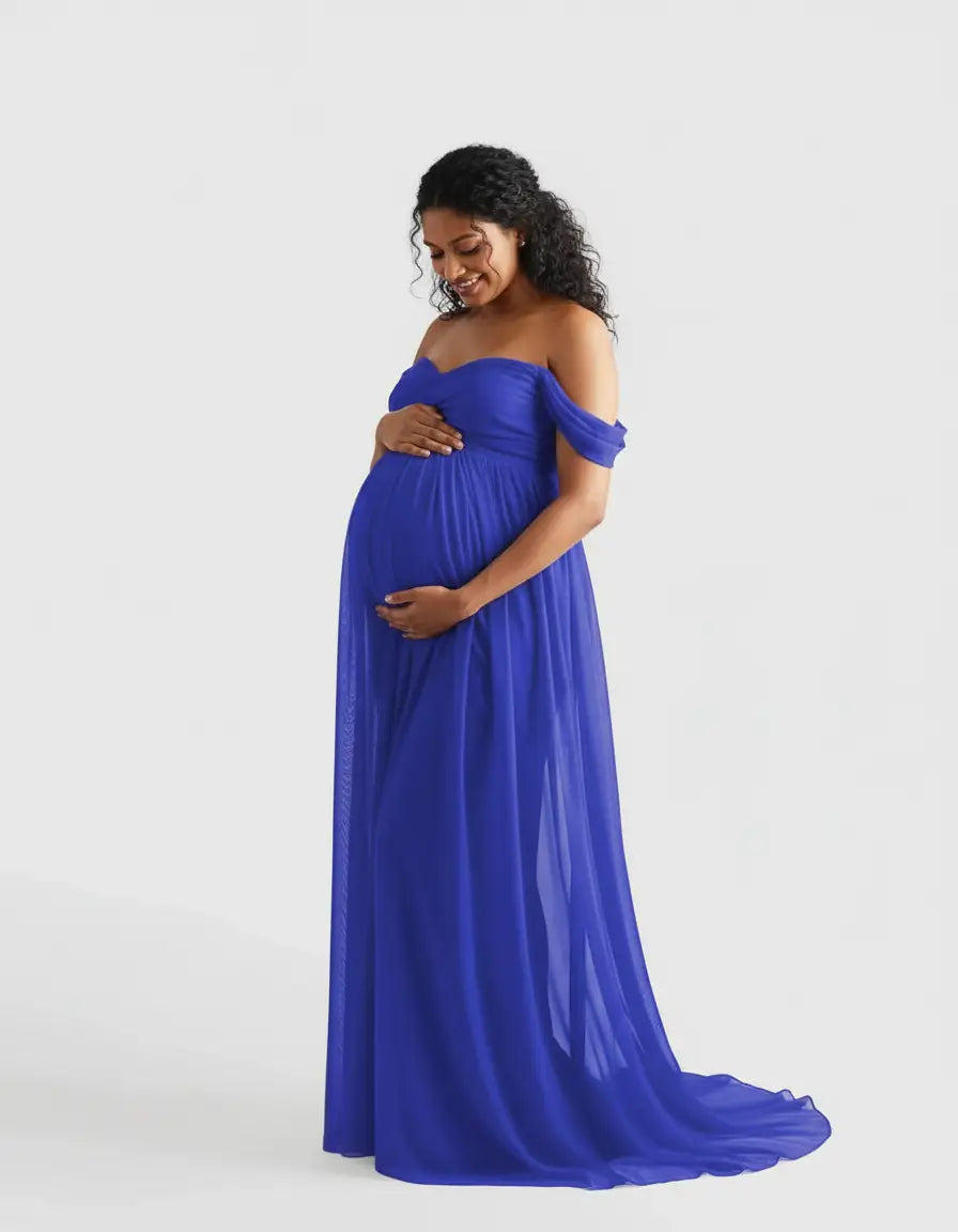 Smiling pregnant woman in a flowing royal blue off-shoulder maternity photoshoot gown.