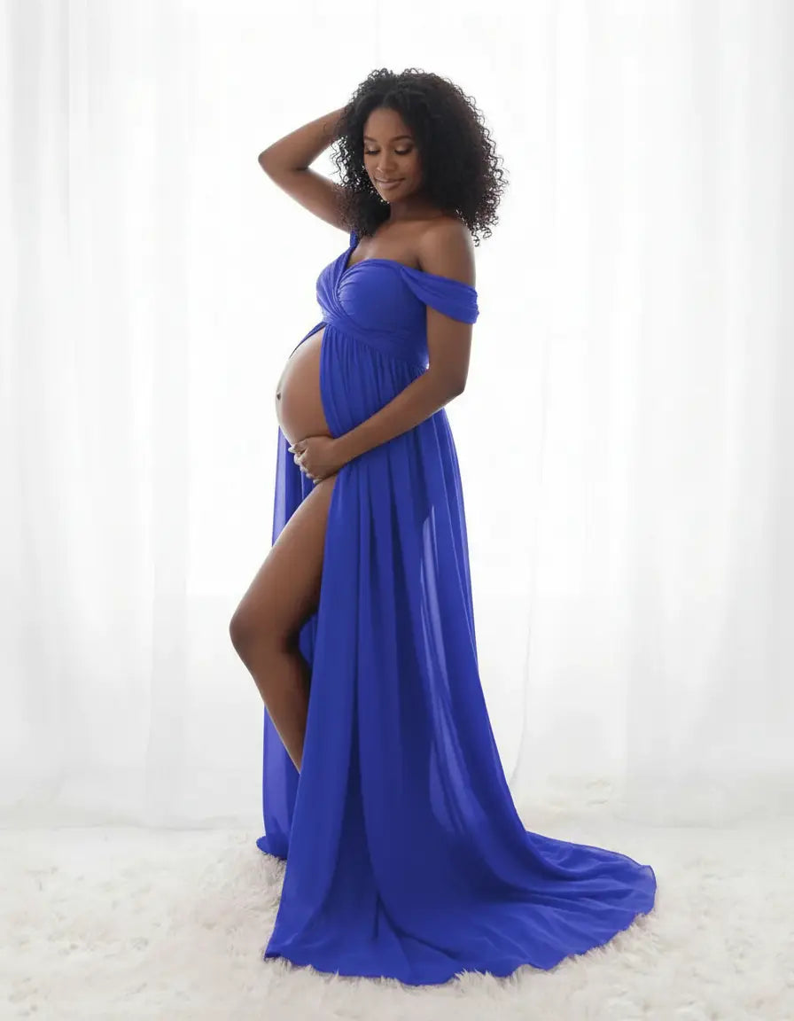 Pregnant woman in a flowing royal blue off-shoulder maternity photoshoot gown with a thigh-high slit.