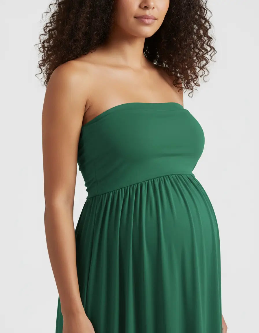 Pregnant woman in a flowing, strapless emerald green maternity gown with a ruched empire waist.