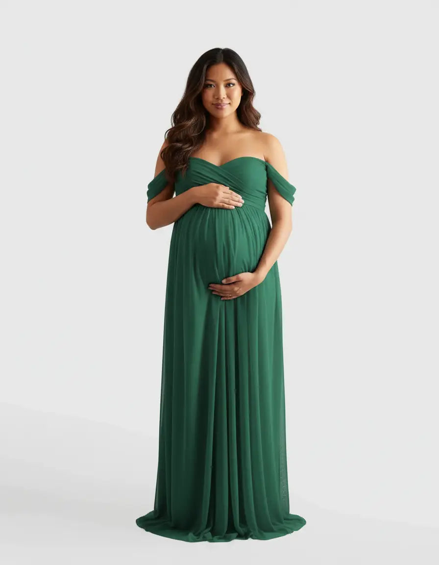 Pregnant woman in a flowing, off-shoulder emerald green maternity photoshoot gown.