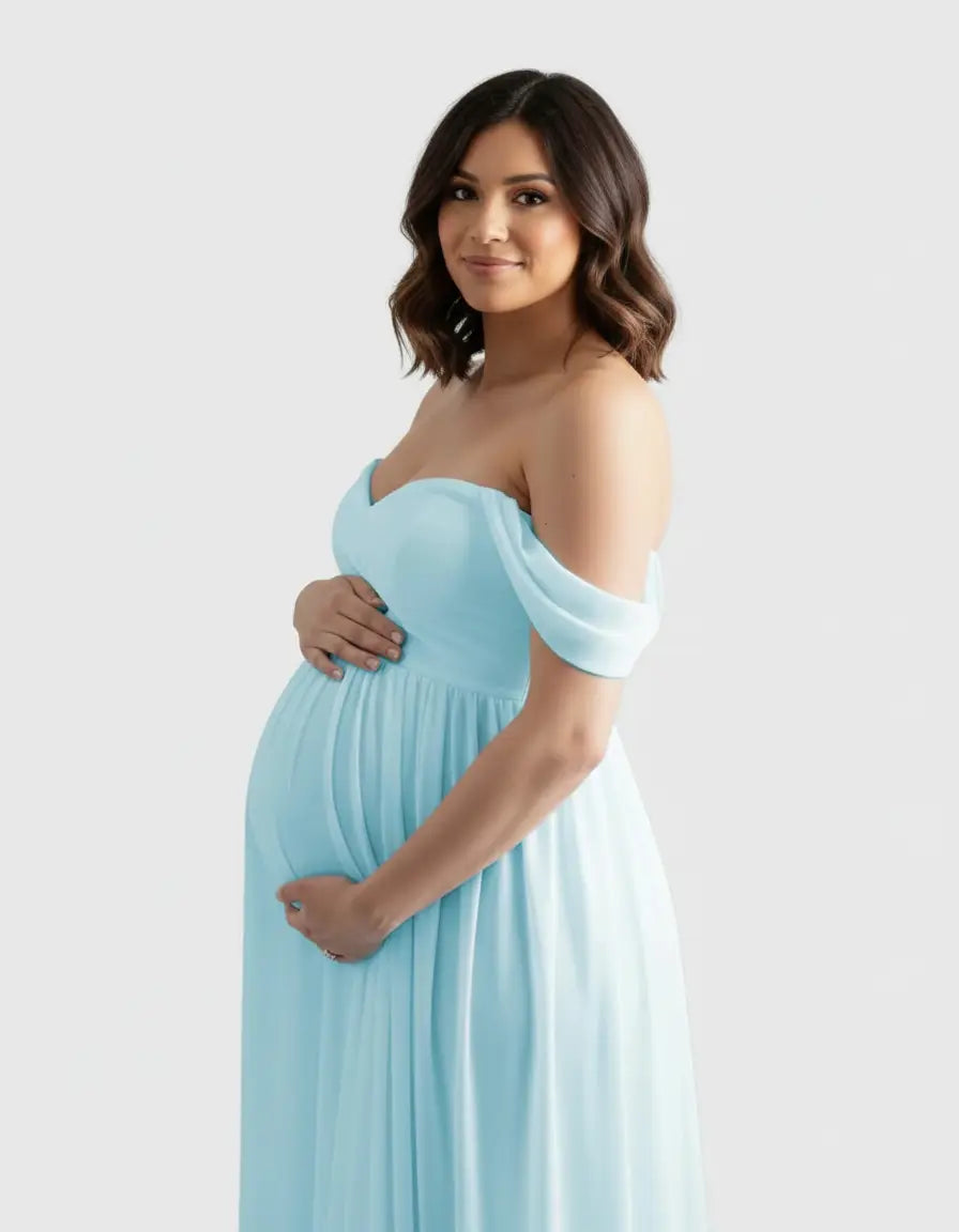 Pregnant woman in a light blue off-shoulder flowing maternity photoshoot gown, holding her baby bump.