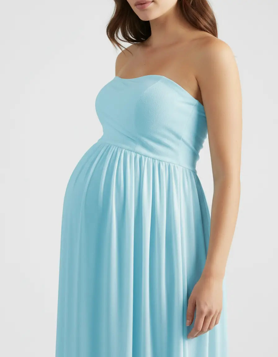 Pregnant woman in a light blue, strapless, flowing maternity photoshoot gown.