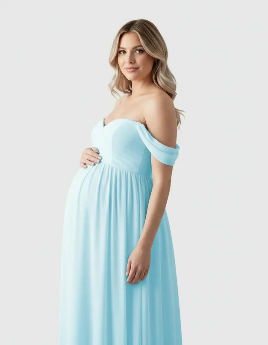 Pregnant woman in a flowing, light blue off-shoulder maternity photoshoot gown.