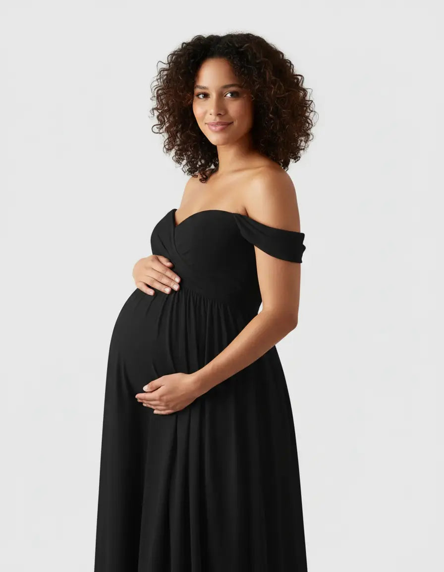 Smiling pregnant woman in a black off-shoulder flowing maternity photoshoot gown.
