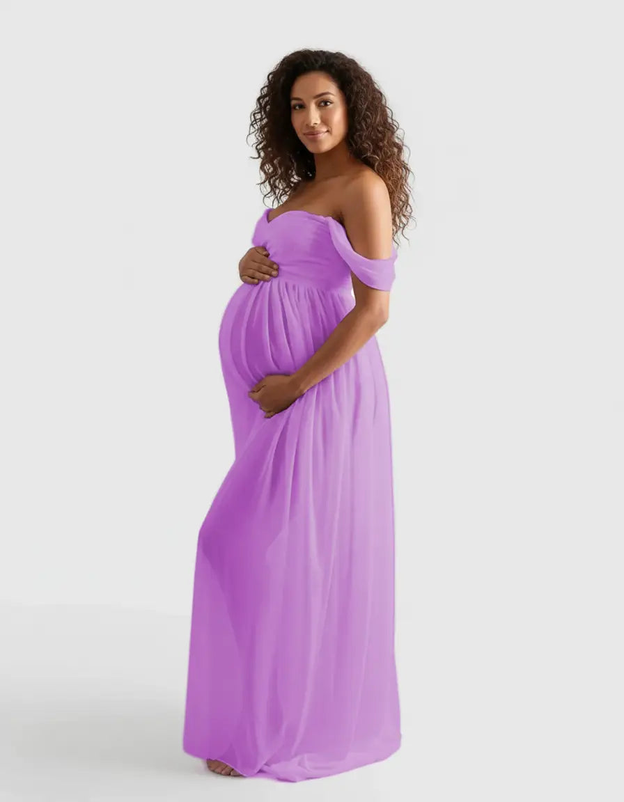 Pregnant woman in a flowing, off-shoulder lavender maternity photoshoot gown, cradling her bump.