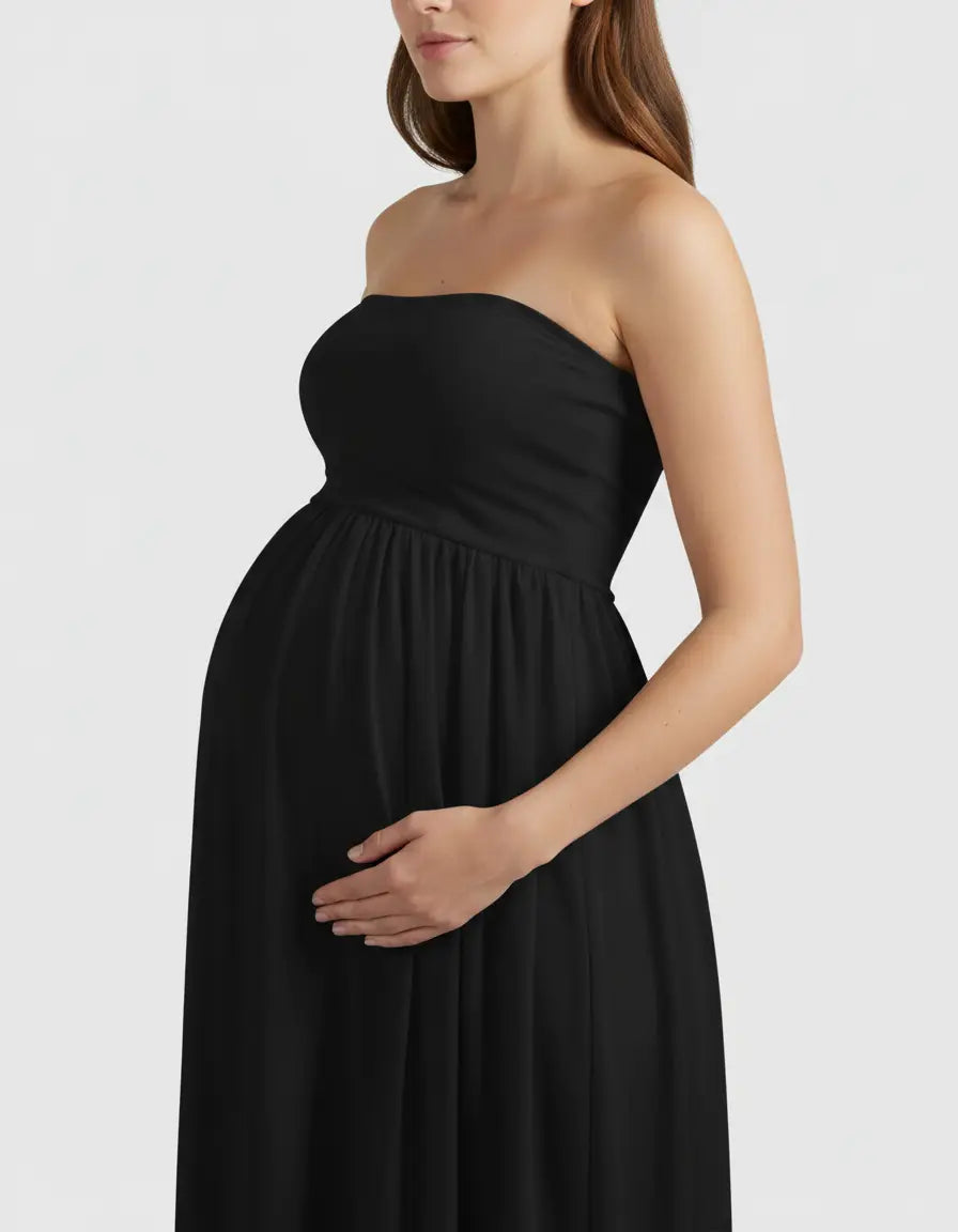 Maternity model in a black strapless flowing gown, hand gently cradling her baby bump.