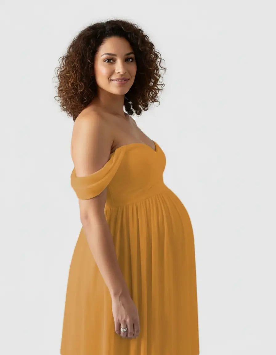 Pregnant woman in a flowing, off-shoulder mustard yellow maternity photoshoot gown.