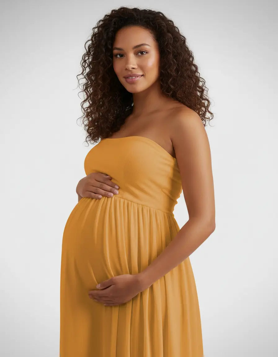 Smiling pregnant woman in a flowing mustard yellow off-shoulder maternity photoshoot gown.