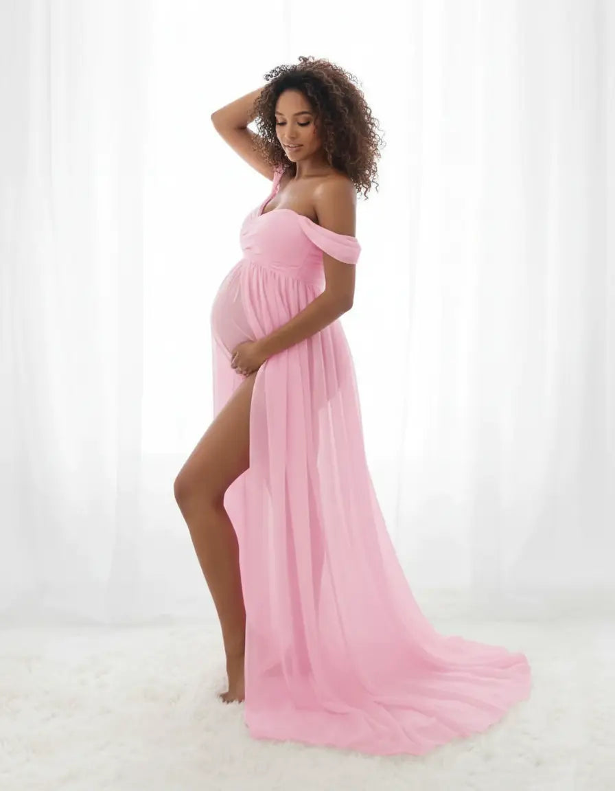 Pregnant woman in a pink off-shoulder flowing maternity photoshoot gown with a high slit.