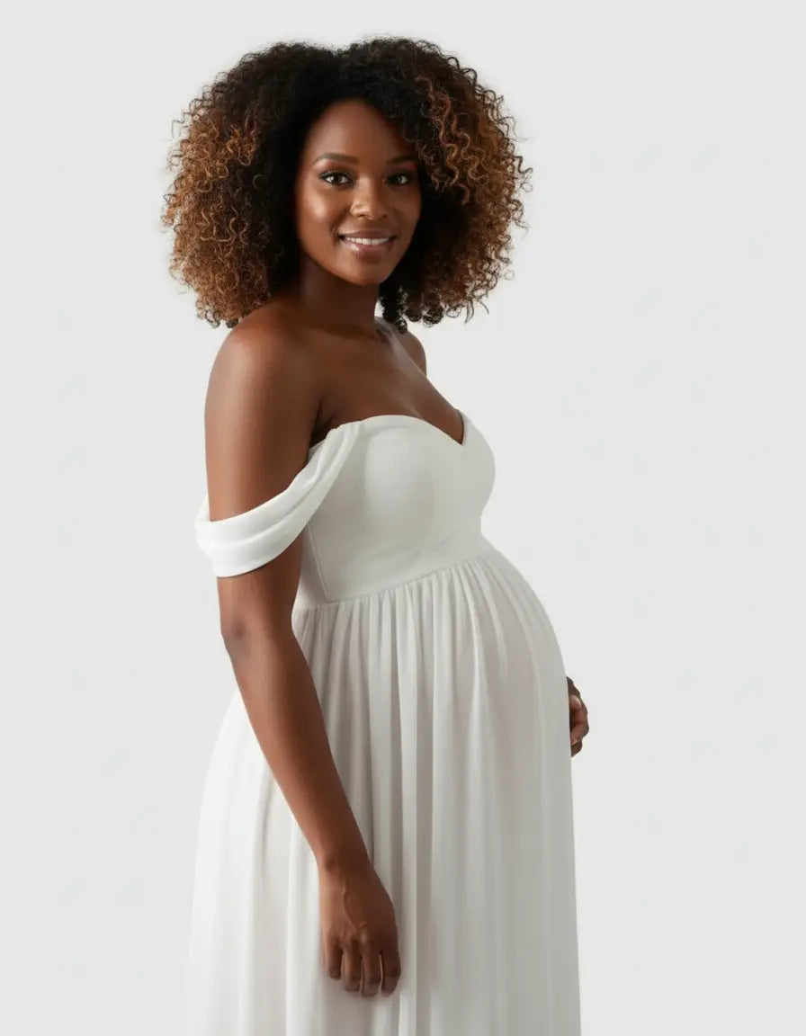 Smiling pregnant woman in a white off-shoulder flowing maternity photoshoot gown.