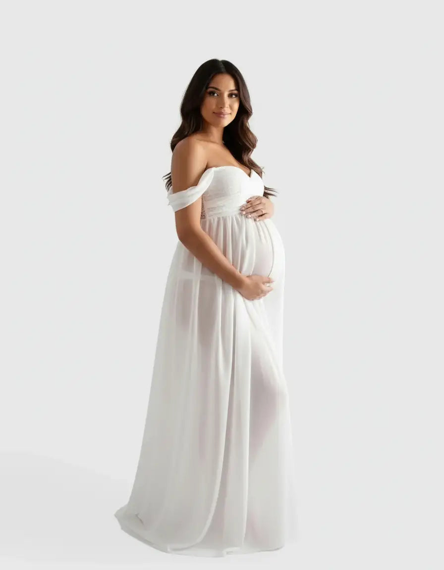Smiling pregnant woman in a white off-shoulder flowing maternity photoshoot gown.