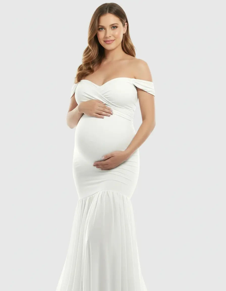 Pregnant woman in a white off-shoulder flowy maternity gown with a sweetheart neckline and mermaid hem.