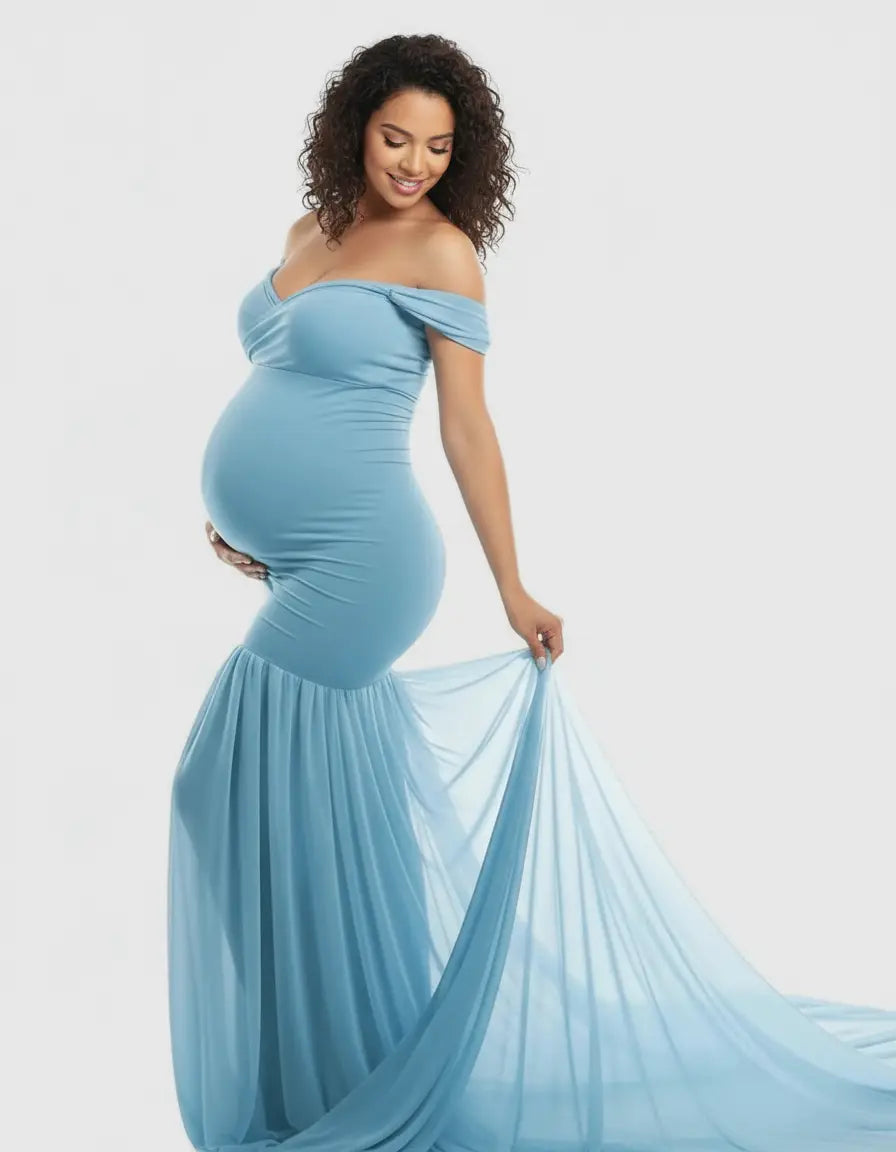 Smiling pregnant woman in a light blue off-shoulder flowy maternity gown with a long train.