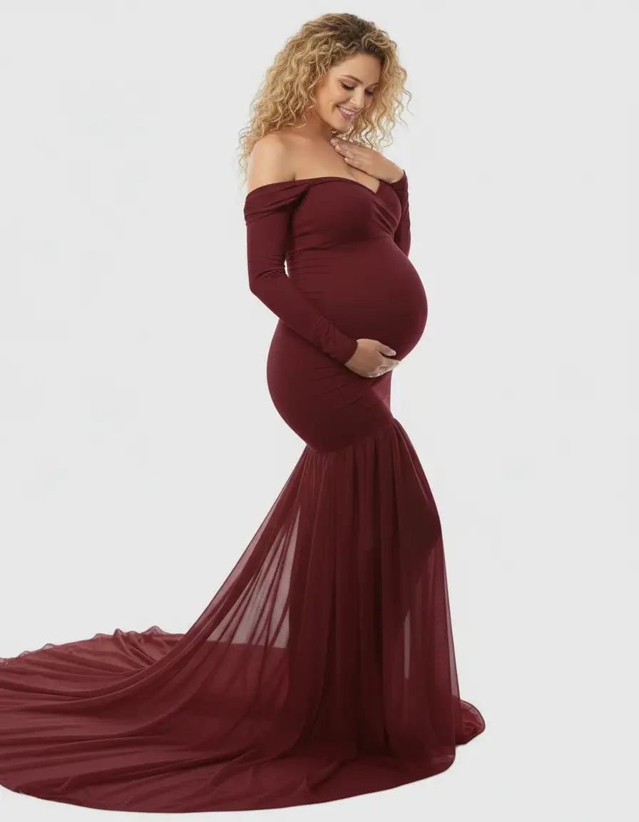 Maternity gown in burgundy with off-shoulder neckline, long sleeves, and a flowing mermaid skirt.