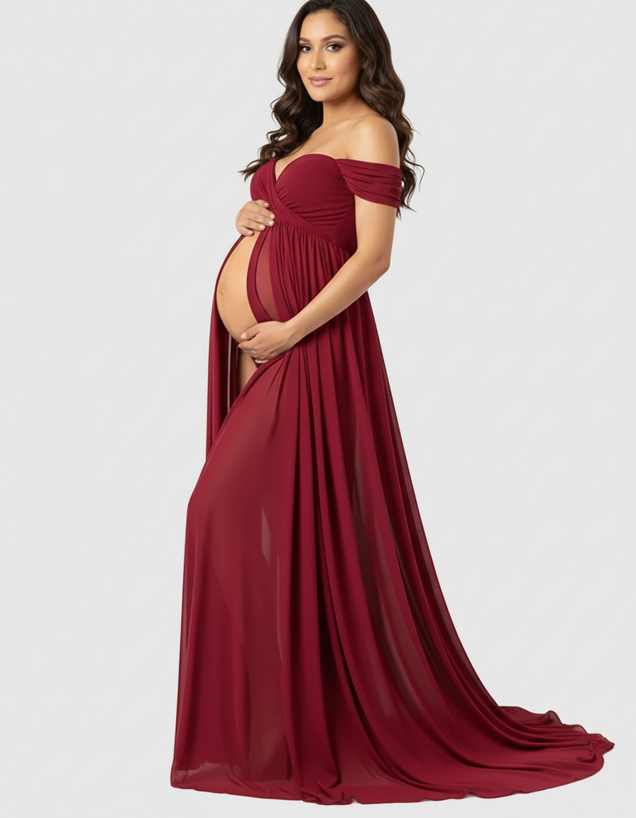 Maternity model in a flowing, off-shoulder, laced burgundy maxi dress with a sheer midriff.