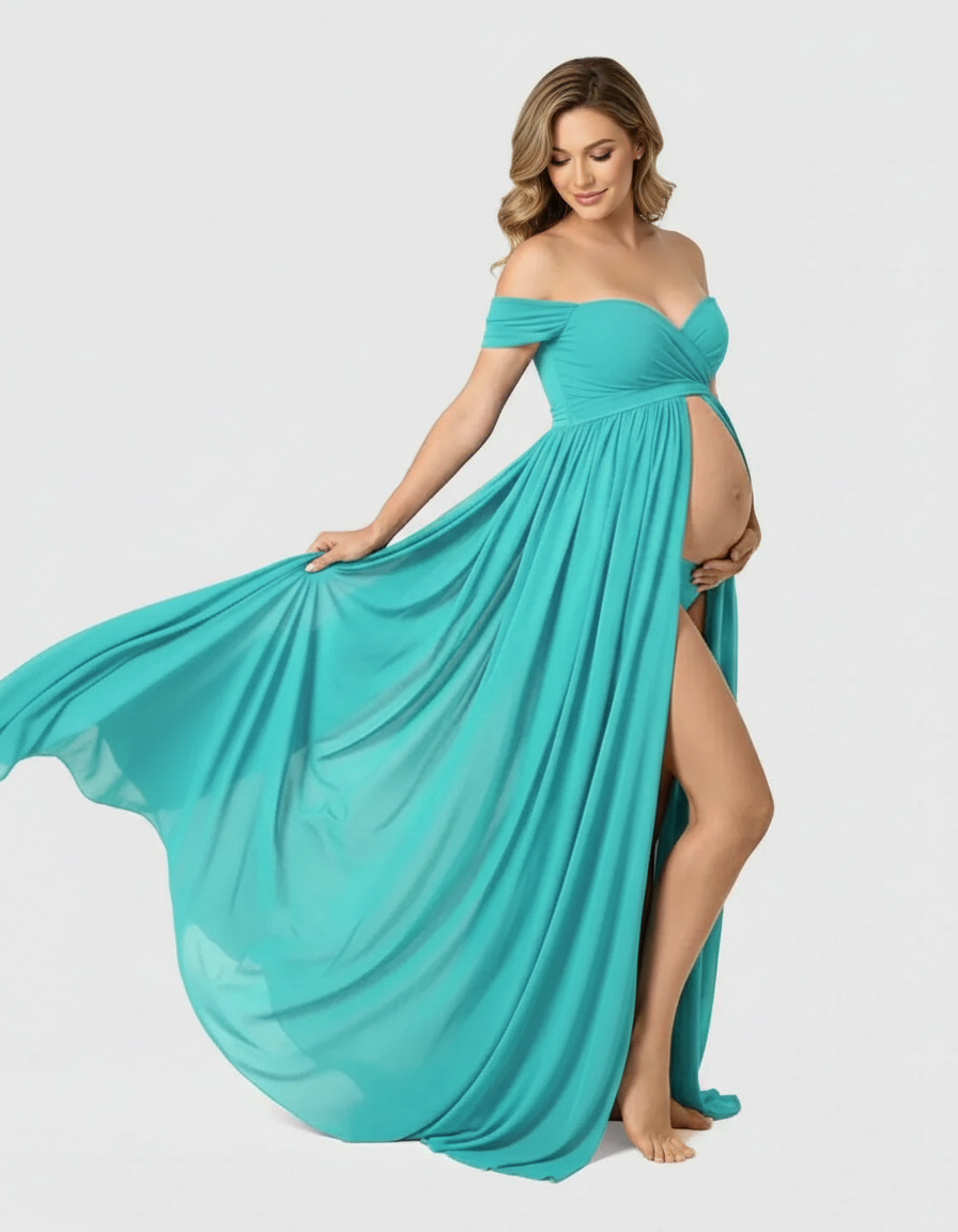 Smiling pregnant woman in a flowing teal off-shoulder maxi dress with a thigh-high slit.