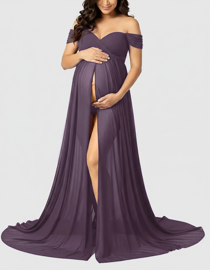 Pregnant woman in a flowing purple off-shoulder maternity maxi dress with a front slit, cradling her bump.
