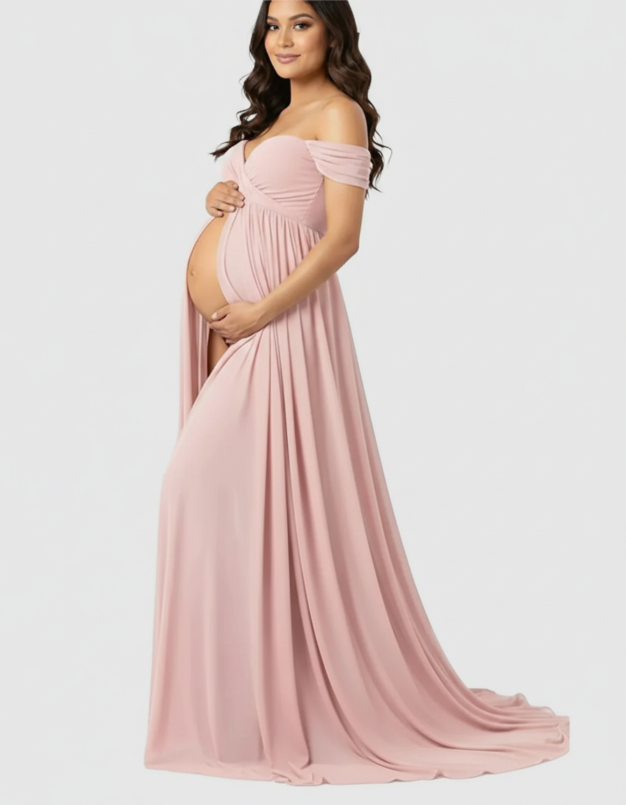 Pregnant woman in a flowing, off-shoulder blush pink maternity maxi dress with a front slit.