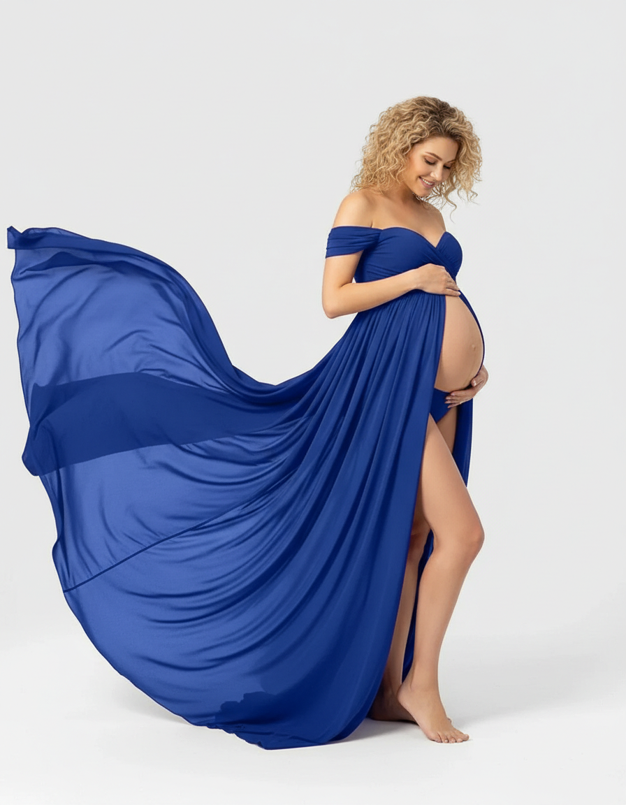 Pregnant woman in a flowing royal blue off-shoulder maternity maxi dress with a high slit.