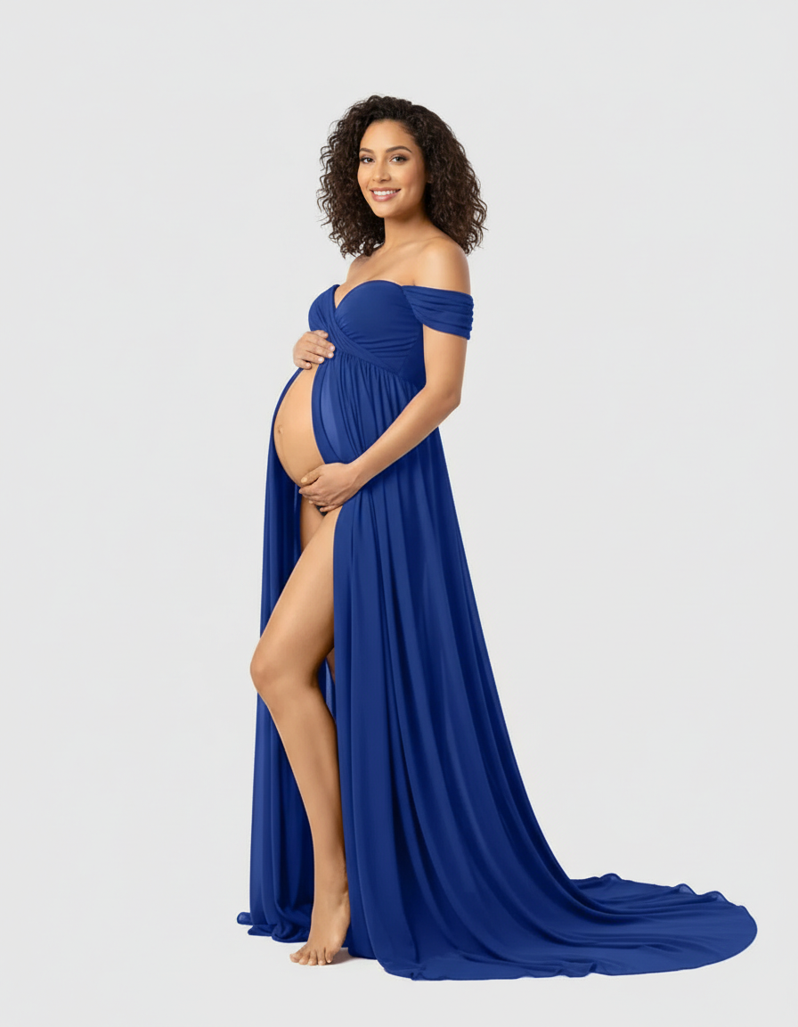 Smiling pregnant woman in a flowing royal blue off-shoulder maternity maxi dress with a thigh-high slit.