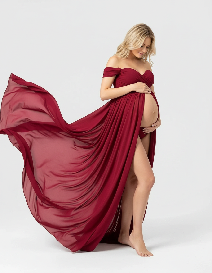 Blonde pregnant woman in a flowing, off-shoulder, laced burgundy maternity maxi dress.