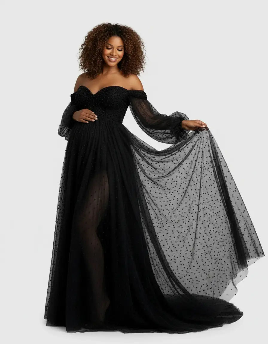 Smiling pregnant woman in a black off-shoulder tulle train maternity gown with polka dots.