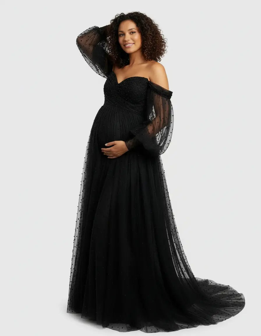Smiling pregnant woman in a black off-shoulder tulle train maternity gown with polka dots.