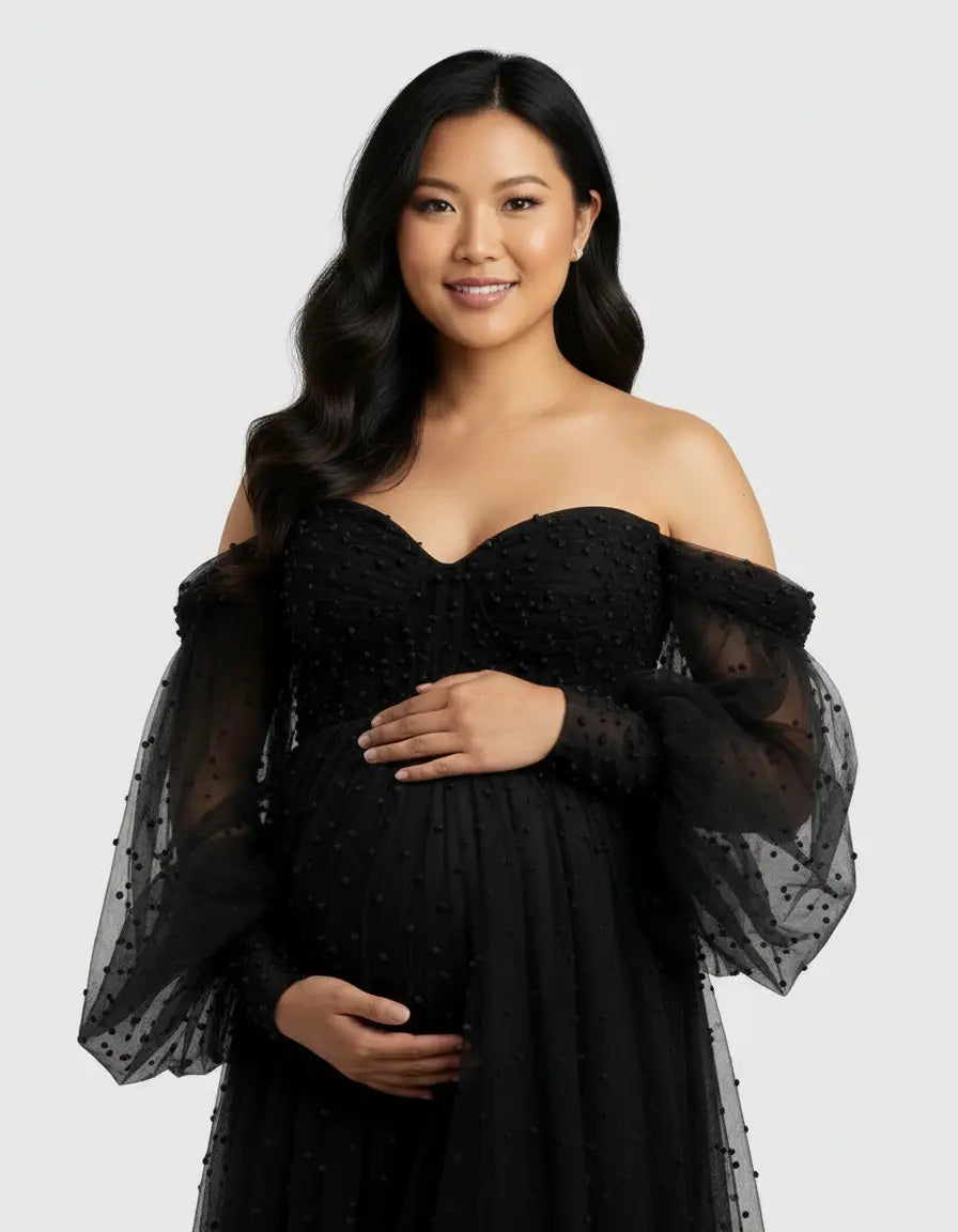 Smiling pregnant woman in a black off-shoulder tulle train maternity gown with polka dots.