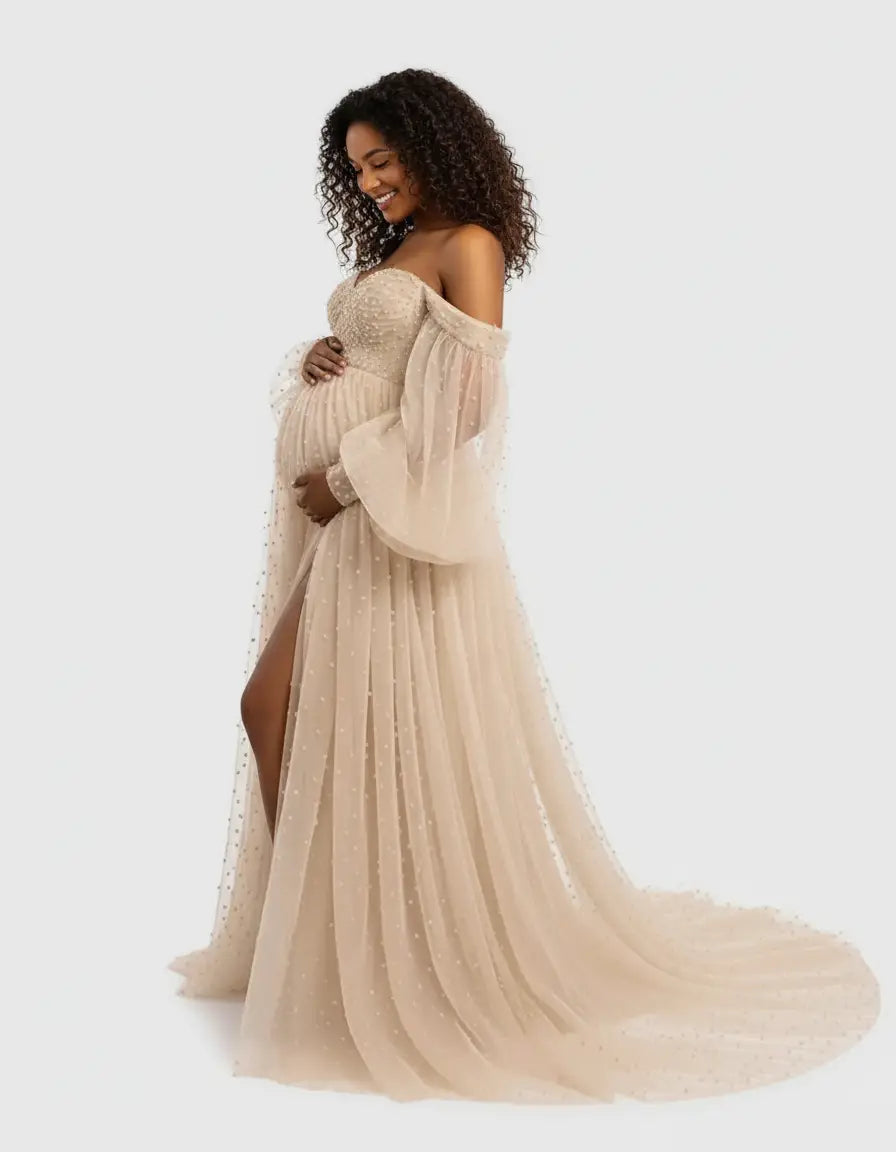 Off-shoulder tulle train maternity gown in champagne with beaded bodice and sheer sleeves.