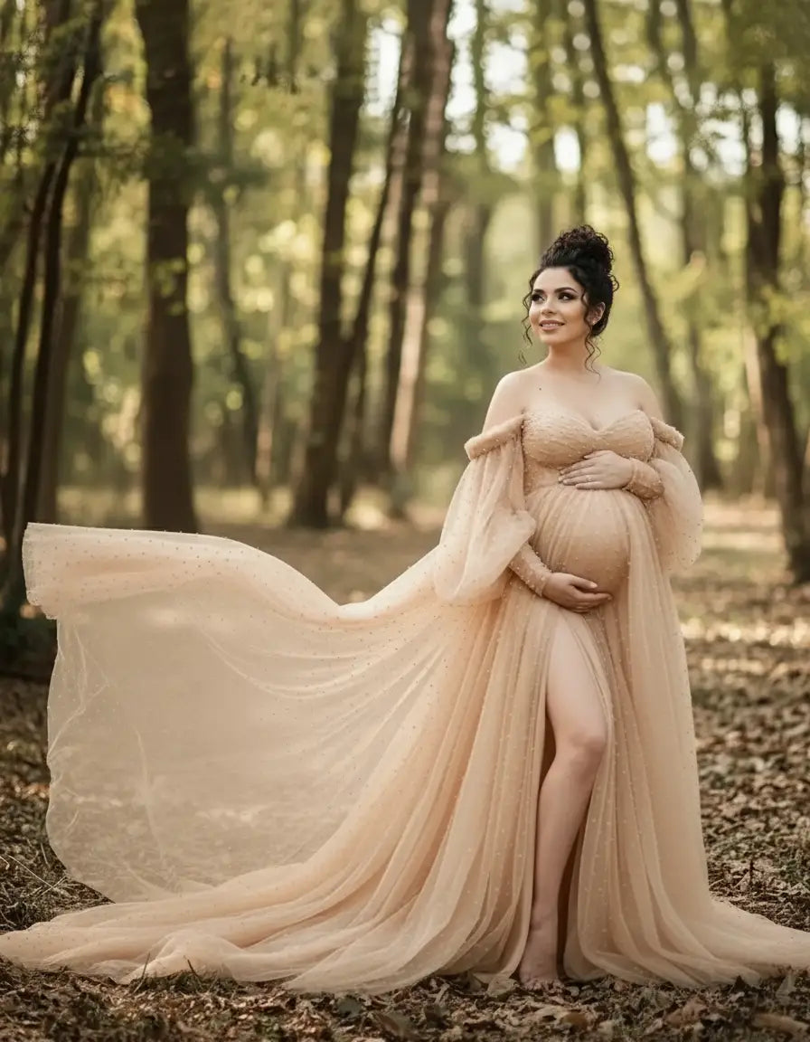 Pregnant woman in a flowing, off-shoulder nude tulle train maternity gown with a thigh-high slit in a forest.