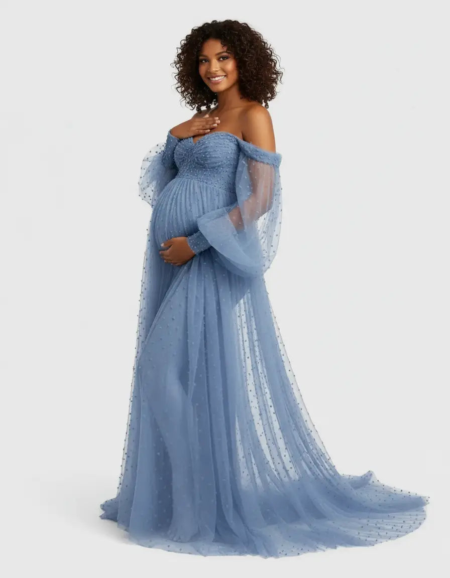 Smiling pregnant woman in a blue off-shoulder tulle train maternity gown with polka dots.