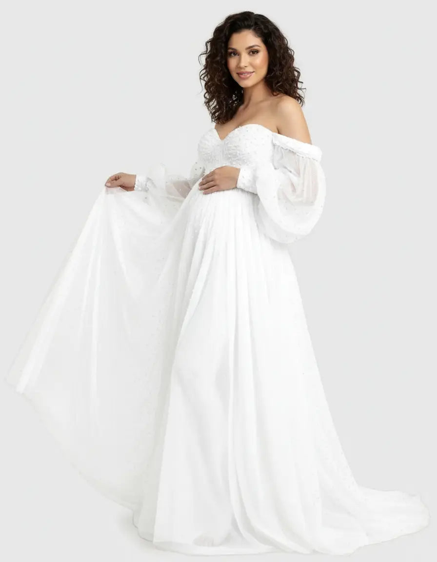 Smiling pregnant woman in a white off-shoulder tulle train maternity gown with balloon sleeves.
