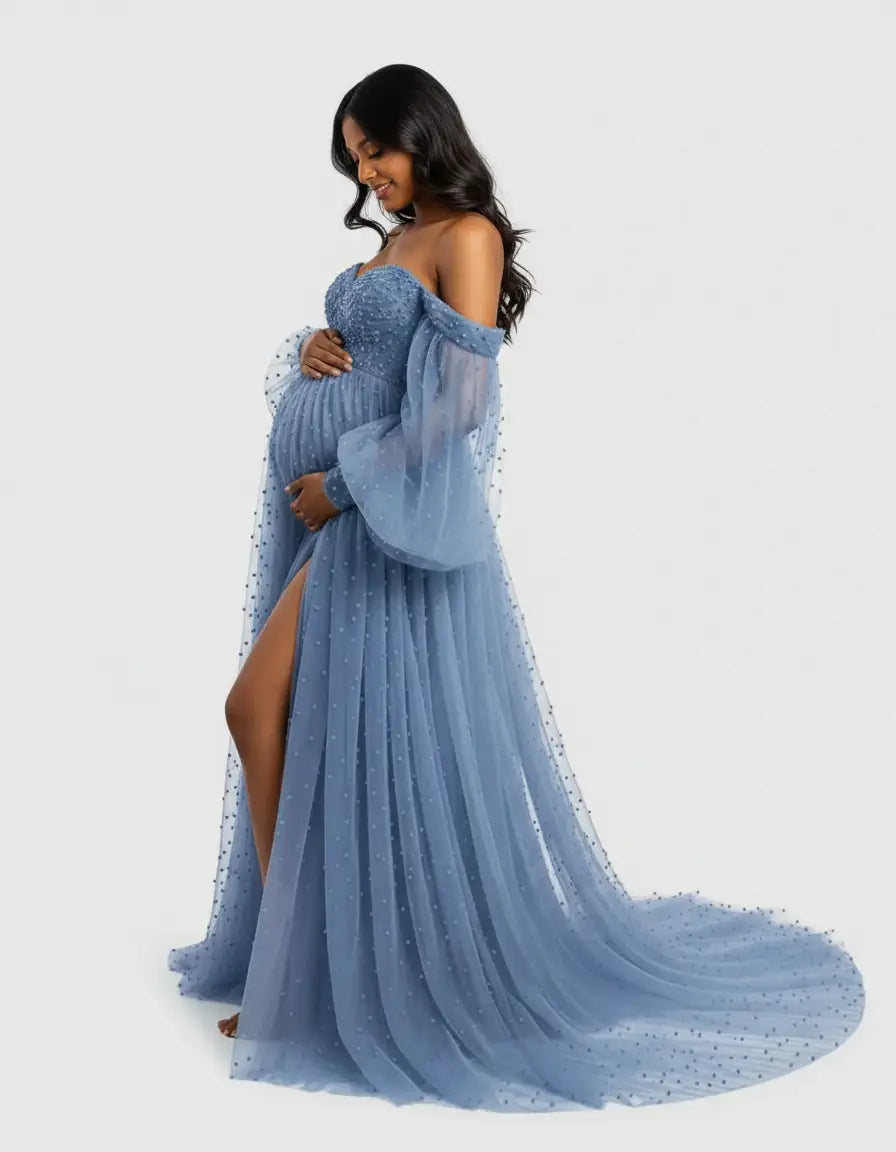 Smiling pregnant woman in a dusty blue off-shoulder tulle gown with a train and delicate pearl embellishments.