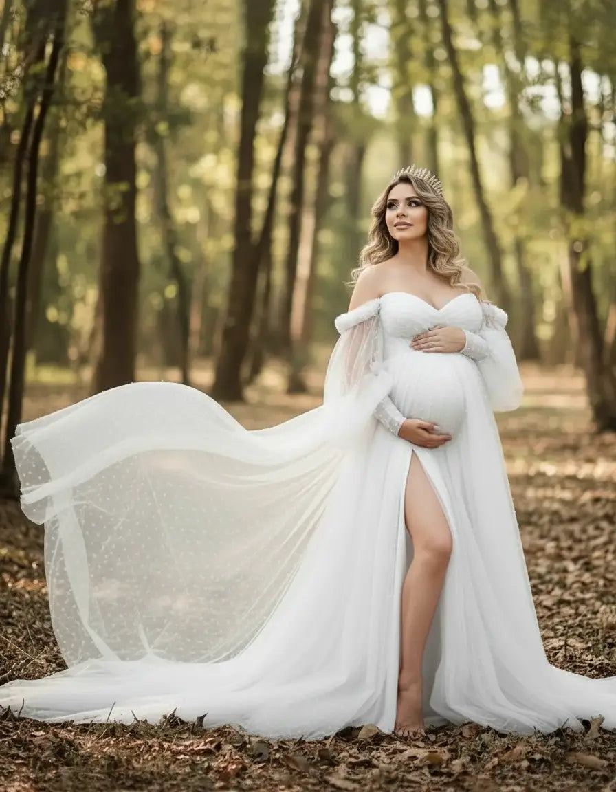 Pregnant woman in a white off-shoulder tulle train maternity gown with a thigh-high slit, posing in a forest.