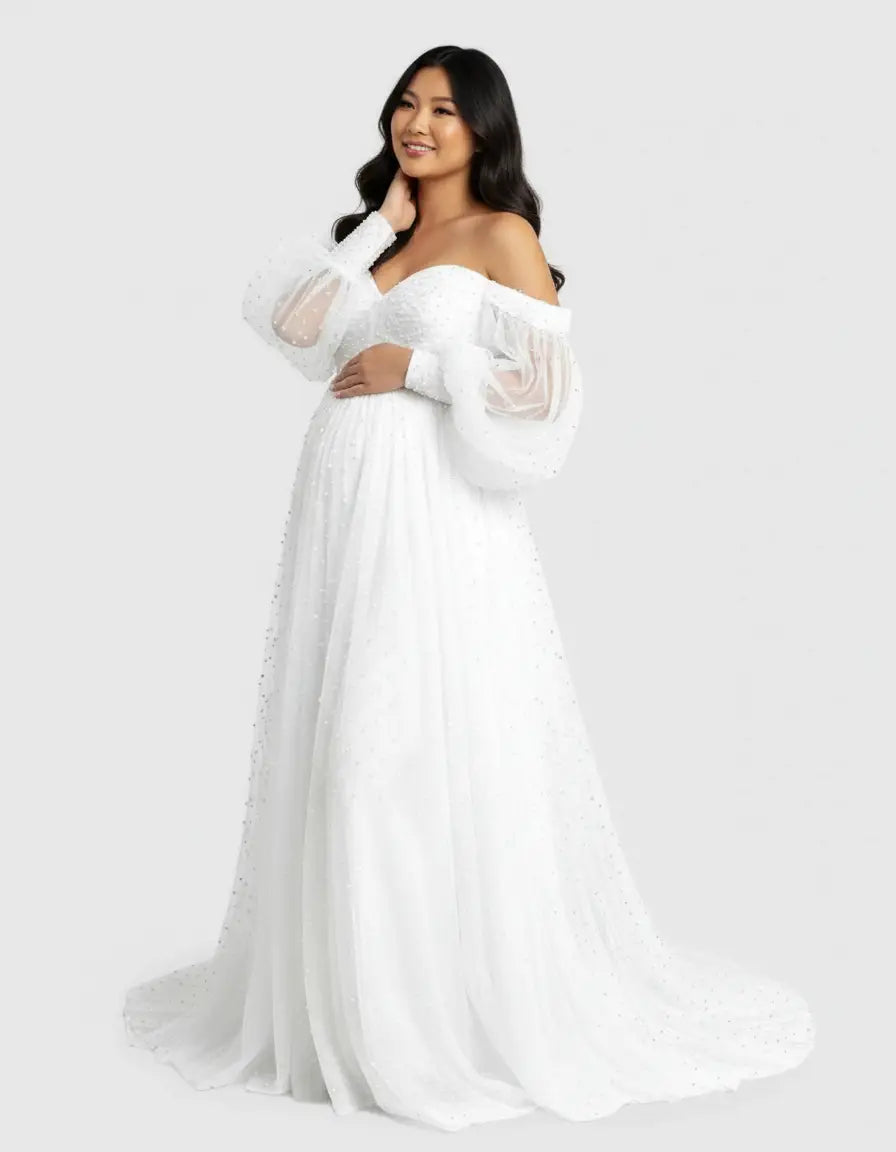 Smiling pregnant woman in a white off-shoulder tulle train maternity gown with pearl accents.