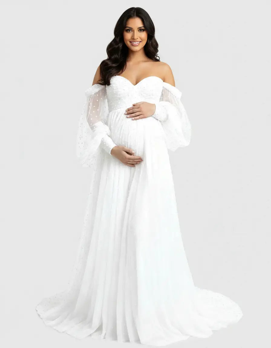 Smiling pregnant woman in a white off-shoulder tulle train maternity gown with polka dot sleeves.