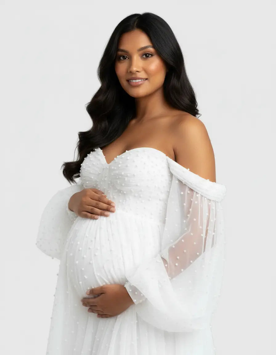 Pregnant woman in a white off-shoulder tulle train maternity gown with pearl details.
