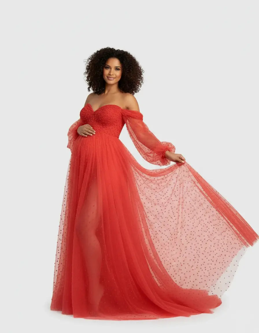 Smiling pregnant woman in a red off-shoulder tulle train maternity gown with subtle polka dots.