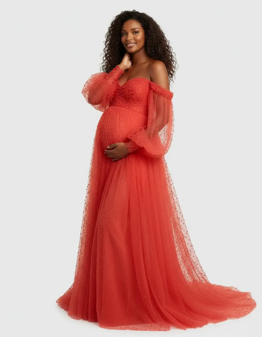 Maternity gown in red tulle with off-shoulder sleeves, beaded bodice, and long train.