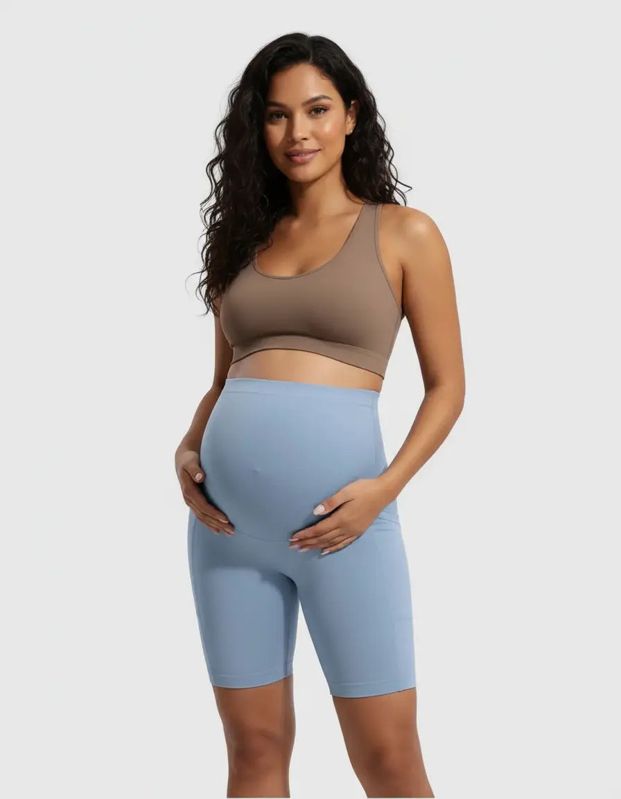 Pregnant woman in a brown bra and light blue over-belly maternity bike shorts with pockets.
