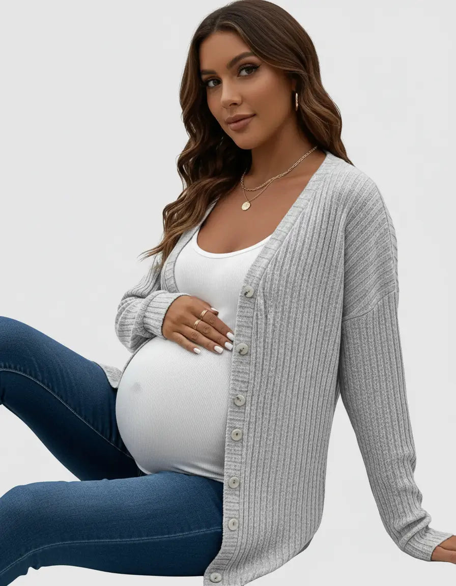 Maternity model in a light gray ribbed button-front drop shoulder cardigan over a white tank top and blue jeans.