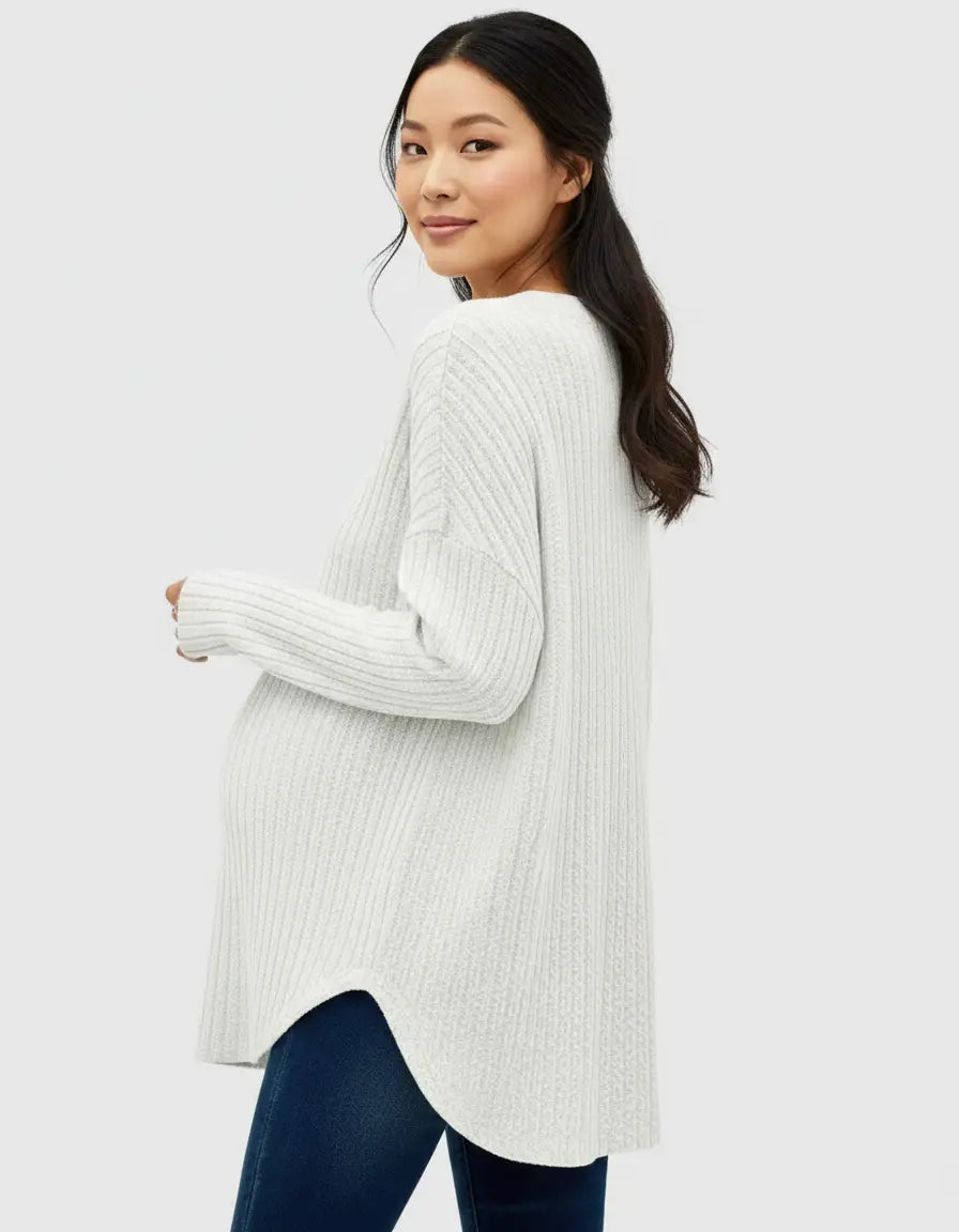 Smiling pregnant woman in a white ribbed drop shoulder maternity top with a rounded hem.
