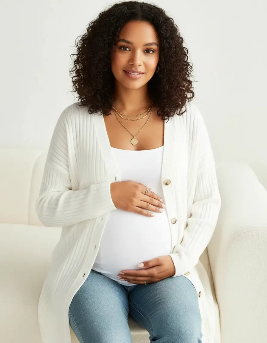 Pregnant woman wearing a white ribbed button-front drop shoulder maternity cardigan over a white tank top.
