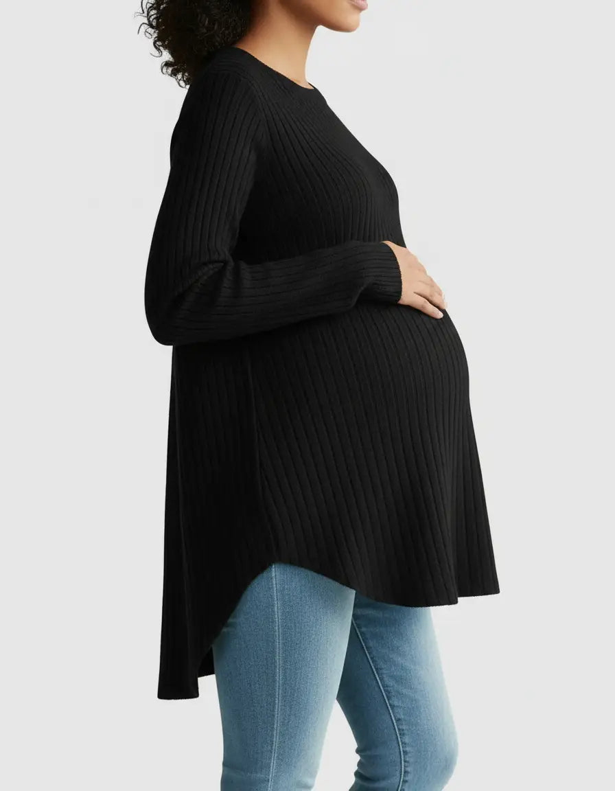 Pregnant woman wearing a black ribbed drop-shoulder maternity top with a high-low hem and blue jeans.